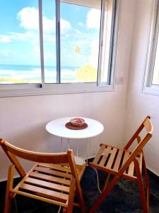 1 mesa y 2 sillas en una habitación con ventana en Sea view cozy apartment, en Haifa
