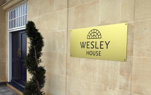 ein Schild für ein Westhaus an der Seite eines Gebäudes in der Unterkunft Wesley House in Cheltenham