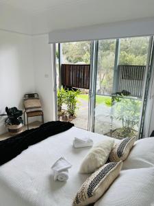 um quarto com uma cama branca com almofadas em URALLA STUDIO - South Coast - Private Guest Suite em Bomaderry