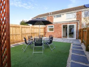 a patio with a table and chairs and an umbrella at Milton House in Weymouth