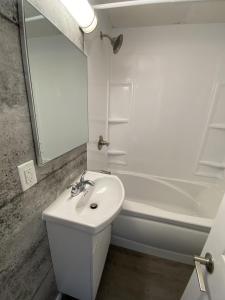 a white bathroom with a sink and a mirror at Le Cardinal in Rouyn-Noranda
