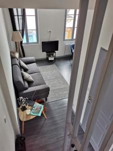 Una sala de estar con un sofá y un televisor. en Comme chez vous, en Le Crotoy
