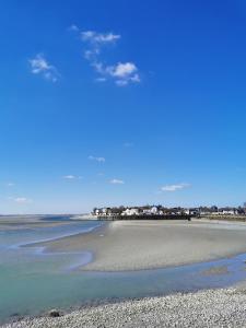 Una vista de la playa con un muelle al fondo. en Comme chez vous, en Le Crotoy