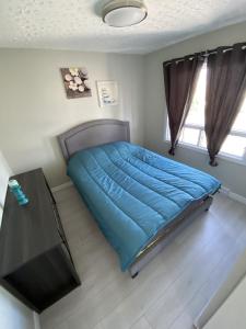 a bedroom with a blue bed and a table at Le Cardinal in Rouyn-Noranda