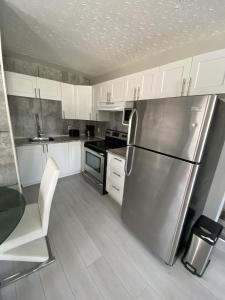 a kitchen with white cabinets and a stainless steel refrigerator at Le Cardinal in Rouyn-Noranda +19 photos