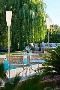 a patio with two chairs and a table with wine glasses at Hotel Bartaccia in Propriano