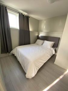 a white bed in a bedroom with a window at Le Cardinal in Rouyn-Noranda