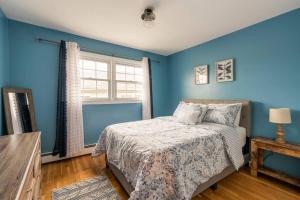 a blue bedroom with a bed and a window at A Suburbia-In-The City Colonial Home in Bayonne