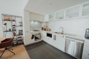 a kitchen with white cabinets and a sink and a table at Beaufort Street Gem 1br Urban Retreat in Perth