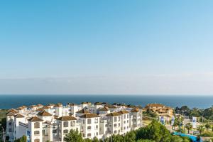 un gran edificio de apartamentos en una colina junto al océano en Apartment Manilva, en Manilva