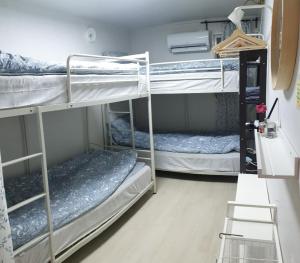 um quarto com 3 beliches e uma escada em Jinho's Guest House em Seul