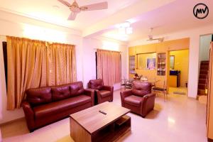a living room with leather furniture and a coffee table at Marigold Villa with Swimming pool in Mahabaleshwar