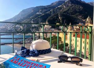 a hat and sunglasses sitting on a table with a view of the mountains at Casa La Voce del Mare in Amalfi