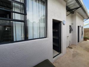 un edificio blanco con ventanas negras y una puerta en 9 Levubu Cottages en Polokwane