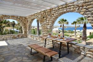 patio ze stołem i kamienną ścianą w obiekcie Executive Paros Villa Villa Avra Sea View and Outdoor Jacuzzi Villa Kostos Damouli w mieście Paros