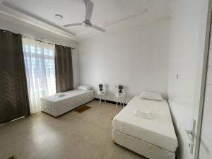 um quarto branco com 2 camas e um sofá em Travellers stay em Dar es Salaam