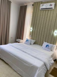 uma grande cama branca num quarto com uma janela em Travellers stay em Dar es Salaam