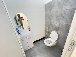 um homem tirando uma foto de uma casa de banho com um WC em Travellers stay em Dar es Salaam