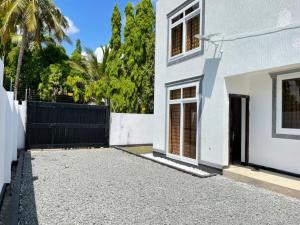 uma casa branca com um portão preto e uma entrada em Travellers stay em Dar es Salaam