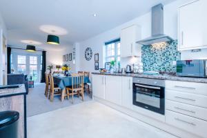 a kitchen with white cabinets and a dining room at Modern 4-Bed Townhouse in Crewe by 53 Degrees Property, Ideal for Contractors & Business, FREE Parking - Sleeps 8 in Crewe