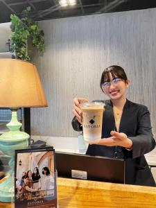 a woman holding up a large cup of coffee at Airo Suites Makati in Manila