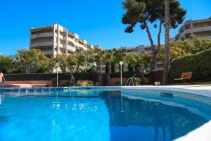 a large blue swimming pool with a building in the background at UHC Buigas Luz Apartments in Salou