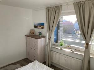Schlafzimmer mit einem Fenster mit Vorhängen und einer Kommode in der Unterkunft Küstenbude Sonne in Grömitz