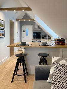 a kitchen and living room with a counter and stools at The Loft Hatch in Kent