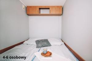 een kleine slaapkamer met een bed met een kopje en een dienblad bij Słoneczne domki in Dębki