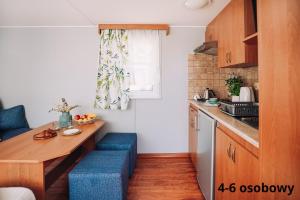 małą kuchnię z drewnianym stołem i niebieskimi stołkami w obiekcie Słoneczne domki w Dębkach