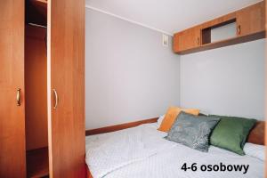 een kleine slaapkamer met een bed en een kast bij Słoneczne domki in Dębki