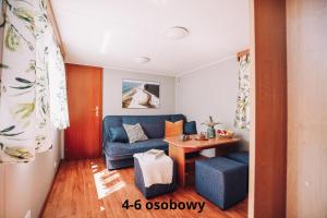uma sala de estar com um sofá azul e uma mesa em Słoneczne domki em Dębki