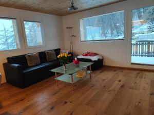 a living room with a black couch and a table at Chalet Matterhornsicht in Naters