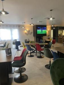 a room with tables and chairs and a tv at Fasthotel Mont de Marsan in Mont-de-Marsan