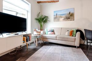 sala de estar con sofá y TV de pantalla plana en Kusthuiskatwijk en Katwijk aan Zee
