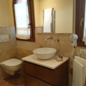 bagno con lavandino, servizi igienici e specchio di S'ena Hotel ad Arbus