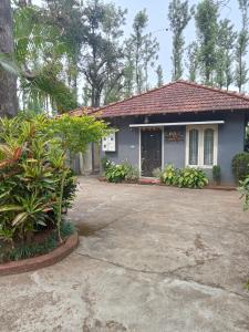 a blue house with a driveway in front of it at FoRest cottage coorg in Madikeri