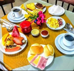 a table with plates of breakfast foods and cups of coffee at Pousada Beija Flores in Porto De Galinhas