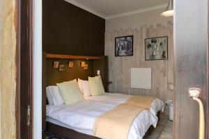 um quarto com uma cama com lençóis brancos e almofadas em Atlantic-Square Guesthouse em Swakopmund