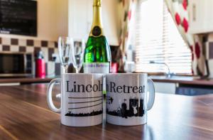 two coffee mugs on a table with a bottle of wine at Lincoln Holiday Retreat Lodge with Private Hot Tub in Lincoln