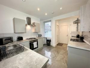 a large kitchen with white cabinets and a counter top at Spacious Five Bed Home in Liverpool