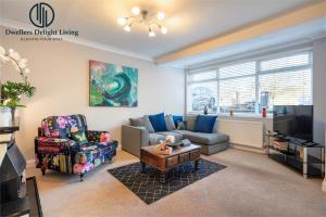 ein Wohnzimmer mit einem Sofa und einem TV in der Unterkunft Dwellers Delight Living Ltd 2 Bed House with Wi-Fi in Loughton, Essex in Loughton