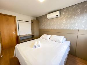 1 dormitorio con 1 cama blanca y 2 zapatillas en LOCAR-IN GRAMADO - Apartamento Residencial Haus, en Gramado
