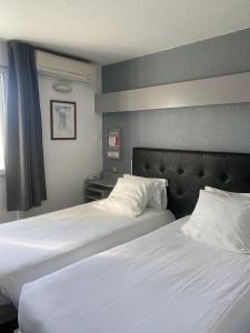 2 camas en una habitación de hotel con sábanas blancas en Fasthotel Mont de Marsan, en Mont-de-Marsan