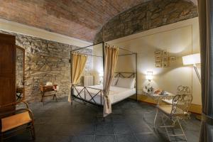 a bedroom with a canopy bed in a stone wall at Porta Castellana B&B - Apartment in Montalcino