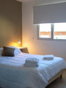 Un dormitorio con una cama blanca con toallas. en Casa Olivia en Ushuaia