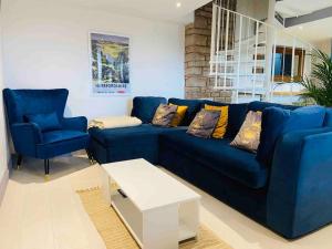 1 sofá azul y 2 sillas en la sala de estar. en The Cider House Holiday Cottage, en Welsh Newton Common
