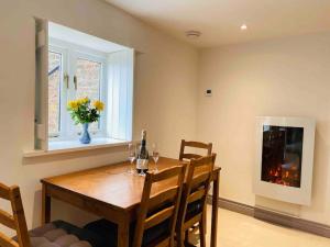 un comedor con una mesa y un jarrón de flores en The Cider House Holiday Cottage, en Welsh Newton Common