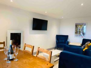 sala de estar con mesa y sofá azul en The Cider House Holiday Cottage, en Welsh Newton Common