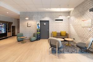 une salle d'attente avec des chaises, des tables et une machine à soda dans l'établissement B&B HOTELS Bourg-en-Bresse Viriat, à Viriat